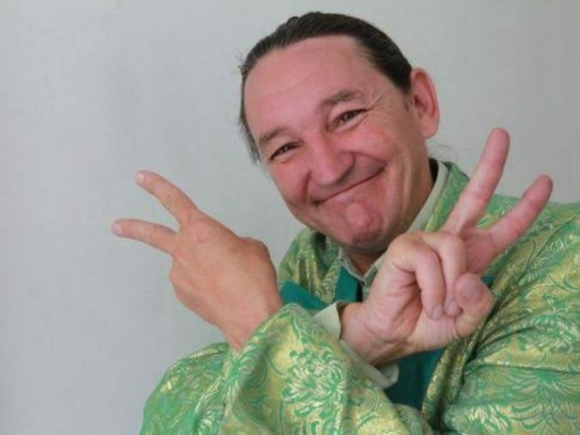Marquito de paletó verde fazendo sinal de paz com as duas mãos